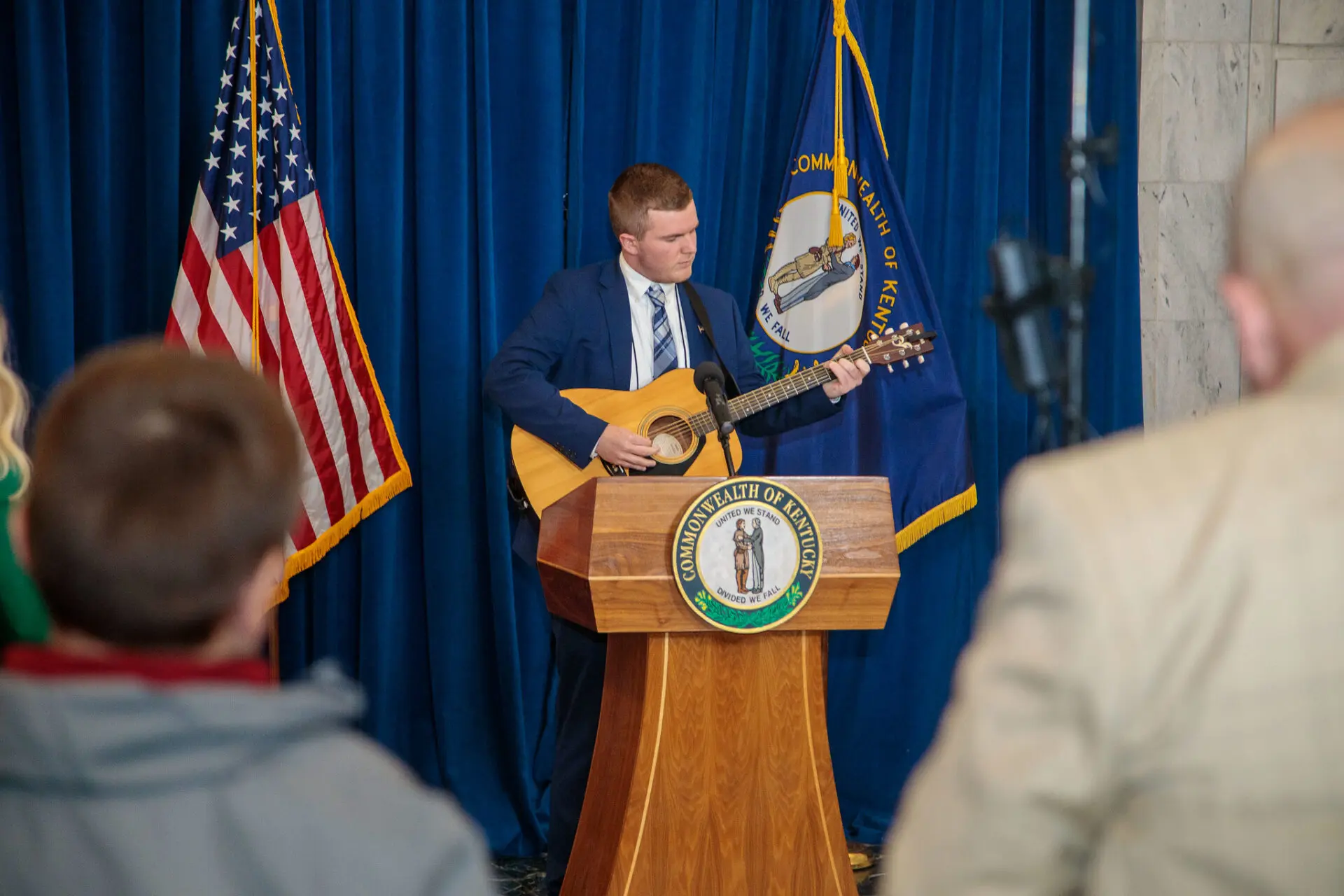 Brady Jones playing guitar at podium on stage